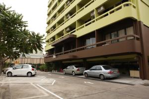 3 auto parcheggiate in un parcheggio di fronte a un edificio di Vintage Studio Apartment Thonglor Ekkamai a Ban Na Song