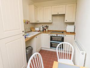 a kitchen with white cabinets and a table and chairs at Butts Hill House in Horton in Ribblesdale