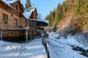 a log cabin in the snow next to a river at LAVANDA country club in Tatariv
