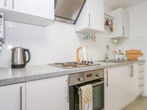 a kitchen with white cabinets and a stove top oven at 5 Firle Road Annexe in Lancing