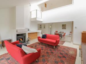a living room with two red chairs and a fireplace at Frater House in Alburgh