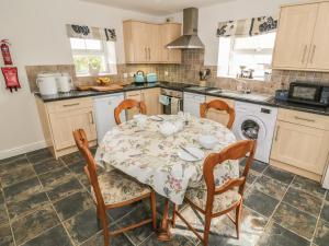 a kitchen with a table and chairs and a sink at Tyn Y Giat in Gaerwen