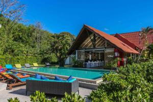 a swimming pool with chairs and a house at Naiharn Beach Resort - SHA Plus Extra in Nai Harn Beach