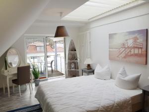 ein weißes Schlafzimmer mit einem Bett, einem Schreibtisch und einem Fenster in der Unterkunft Ostseeblick Baabe in Baabe