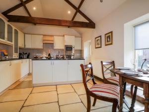 CanonbieにあるCarwinley Mill House Cottageの白いキャビネット、テーブルと椅子付きのキッチンが備わります。