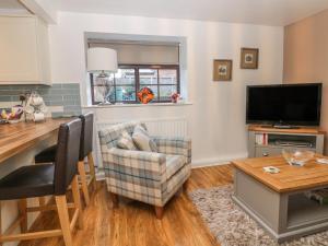 sala de estar con mesa, TV y silla en Glebe Hall Apartment en Marske-by-the-Sea