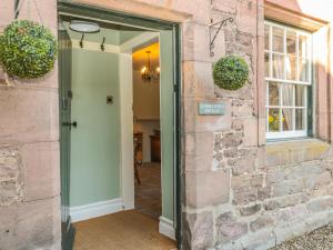 una porta che conduce in una camera con un muro di mattoni di Gamekeepers Cottage a Chillingham