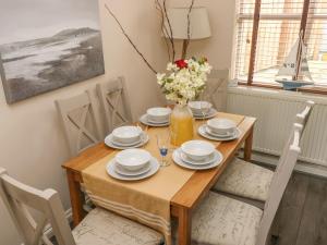 a dining room with a wooden table and chairs at Sandy Bay House in Saundersfoot