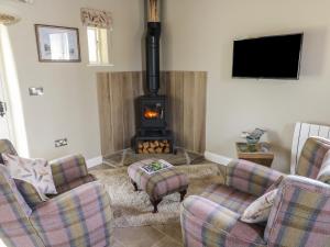 a living room with two chairs and a stove at Saetr Cottage in Harrop Fold
