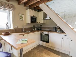 Harrop FoldにあるSaetr Cottageのキッチン(白いキャビネット、木製カウンタートップ付)