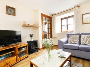 a living room with a couch and a tv and a table at The Shippon in Launceston