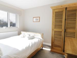 ウィンダミアにあるUpper Oaksのベッドルーム1室(ベッド1台付)、木製キャビネットが備わります。