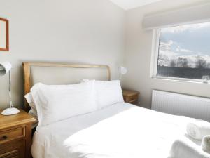 ein Schlafzimmer mit einem weißen Bett und einem Fenster in der Unterkunft Upper Oaks in Windermere