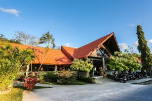 un edificio con techo anaranjado con motocicletas aparcadas delante en Naiharn Beach Resort - SHA Plus Extra, en Nai Harn Beach