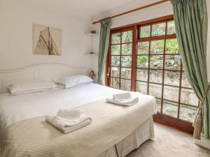 a bedroom with a white bed and a window at Mengarth in Cadgwith