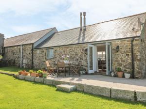 a stone house with a patio and a table at Back Of Beyond in Treen
