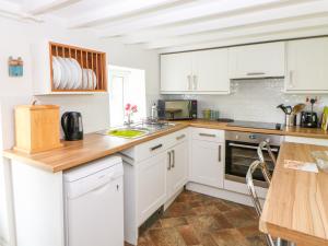 een keuken met witte kasten en een houten aanrecht bij Broom Cottage in East Rudham