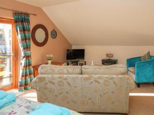 ein Wohnzimmer mit einem Sofa und einem TV in der Unterkunft The Loft in Bradwell