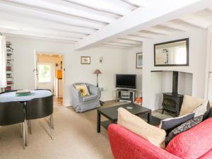 a living room with a red furniture and a fireplace at Broom Cottage in East Rudham
