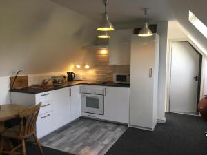 a kitchen with white cabinets and a table and a chair at The Steppes Holiday Cottages in Hereford
