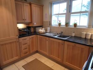 uma cozinha com armários de madeira, um lavatório e uma janela em Daisy Cottage em Uny Lelant