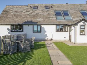 a house with a table and chairs in the yard at Bluebell Cottage in Ulverston