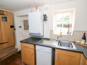 a kitchen with a sink and a white refrigerator at Flint Cottage in Swaffham