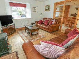 a living room with leather couches and a tv at Bridge House in Hawes