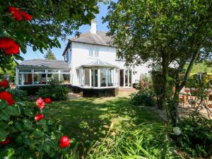 a white house with a porch and red roses at Grange Farm Cottage in Sutton Bridge