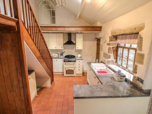 a kitchen with a sink and a stove top oven at Holly Cottage in Matlock