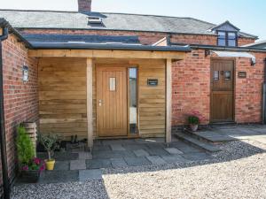 a wooden shed with two doors and a brick building at Stables Cottage in East Norton