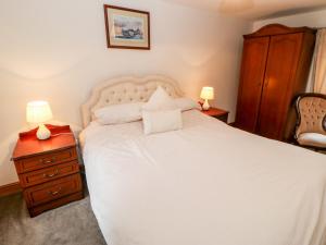 a bedroom with a large white bed with two lamps at The Hayloft in Brampton