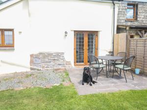 a black dog sitting next to a table and chairs at Lower West Curry Cottage in Launceston