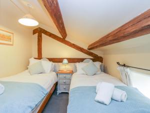 two twin beds in a room with wooden beams at Swallow Cottage in Scarborough