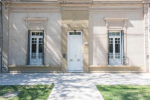 a white building with two windows and a white door at La Casona Apart Boutique in Marcos Juárez
