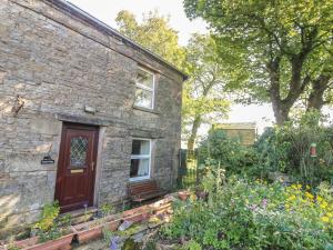 a stone house with a red door and a garden at Sycamore Cottage in Cotterdale +12 photos
