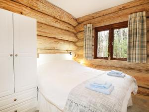 a bedroom with wooden walls and a bed with towels on it at Moorhen Lodge in Inverness