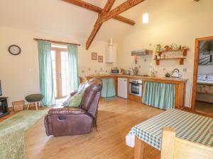 a living room with a leather chair and a kitchen at Lily Cottage in Caernarfon