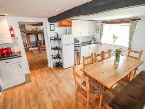 uma cozinha e sala de jantar com uma mesa de madeira em Hill Farm Cottage em Freshwater