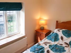 a bedroom with a bed and a window at Rose Cottage in Chard