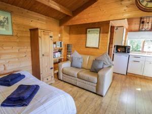 a bedroom with a bed and a couch in a cabin at The Log Cabin in Kilmore
