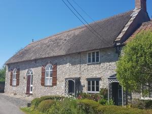 an old stone house with a roof at Rose Cottage in Chard