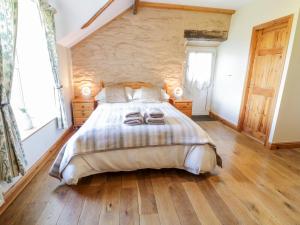 a bedroom with a large bed and a stone wall at Tyddyn in Dyffryn