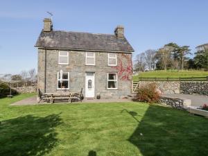 une ancienne maison en pierre avec un banc dans la cour dans l'établissement Tyddyn, à Dyffryn