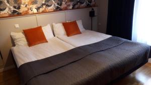 ein großes Bett mit zwei orangenen Kissen darauf in der Unterkunft Dinners in Arboga