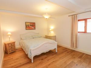 a bedroom with a white bed and two night stands at Hen Stabl in Beaumaris