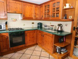 uma cozinha com armários de madeira e um forno com placa de fogão em Brook Cottage em Hayfield