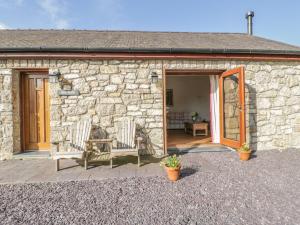 a stone cottage with two chairs and a door at Hen Stabl in Beaumaris