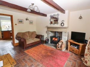 a living room with a couch and a fireplace at Brook Cottage in Hayfield