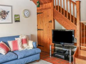 uma sala de estar com um sofá azul e uma televisão em The Dairy em Buxton